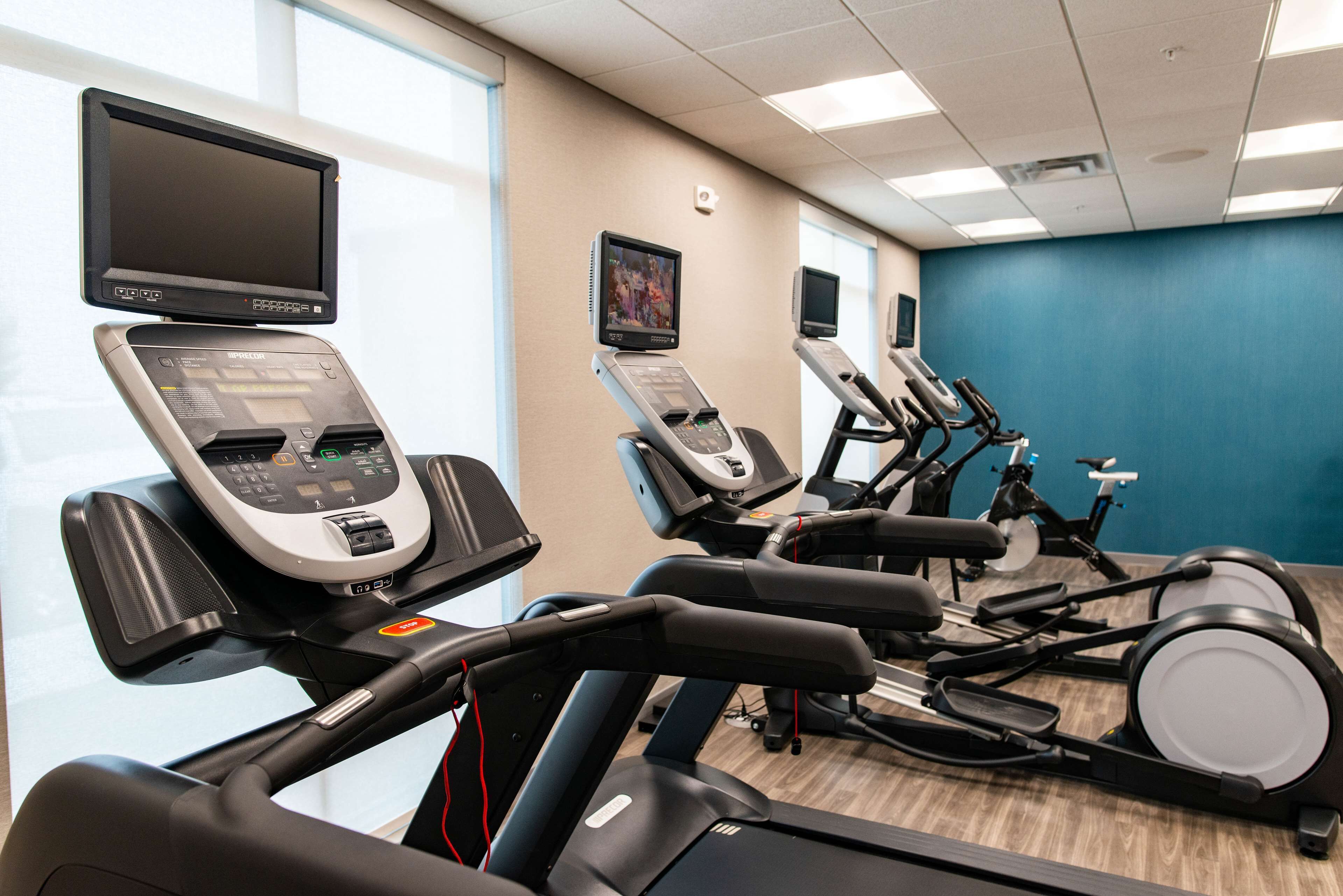 Ein Fitnessraum mit mehreren Laufbändern und Ergometer, ausgestattet mit digitalen Bildschirmen und Bedienfeldern.