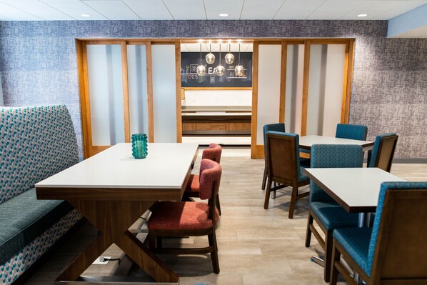 Un comedor con una mesa larga y varias sillas, un sofá, y una cocina al fondo.