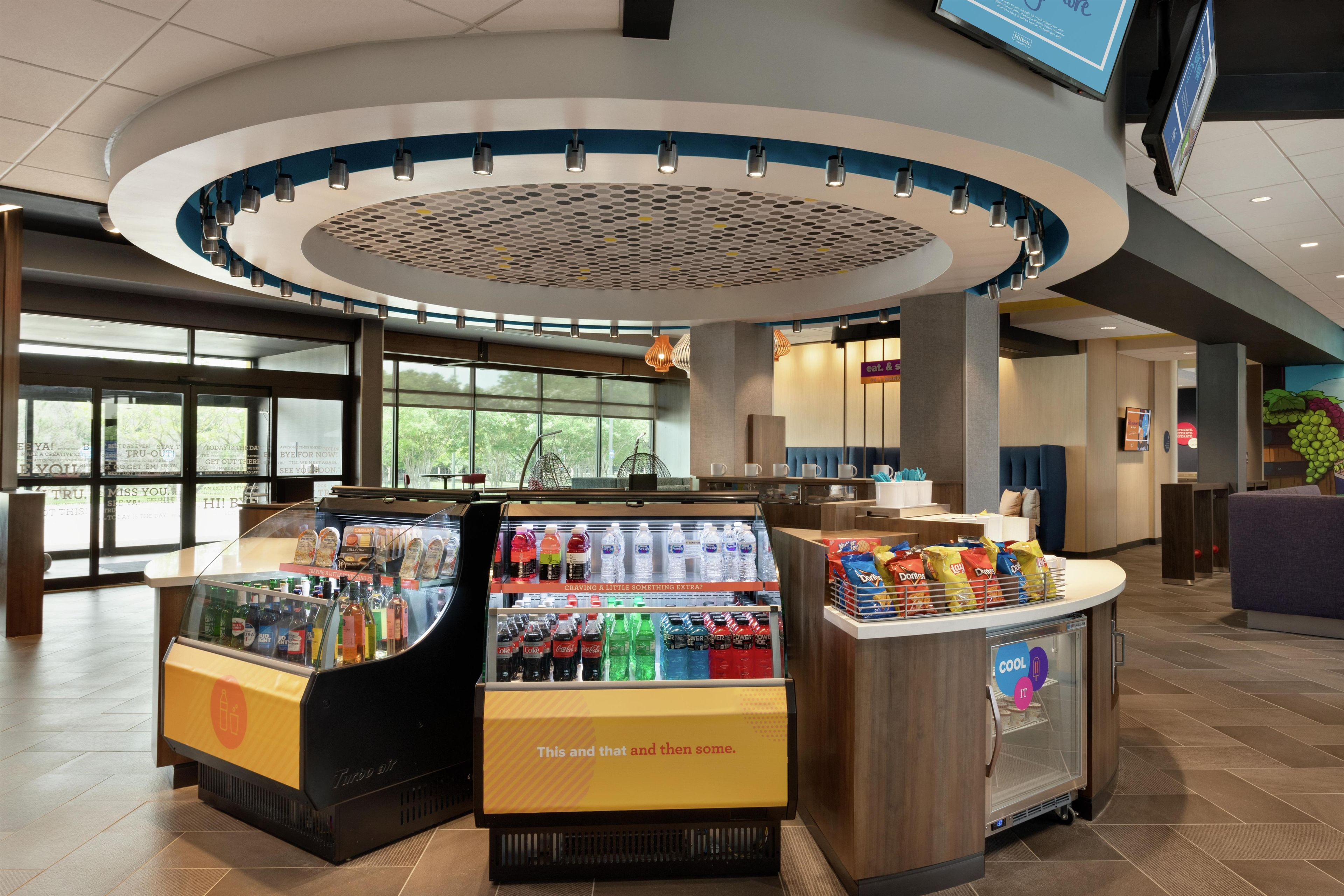 A hotel lobby with a beverage display, a reception desk, and a large window providing natural light.