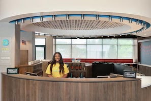 A hotel reception desk with a modern design, a large window, and a digital display. - Tru By Hilton Frisco Dallas, TX (Frisco)