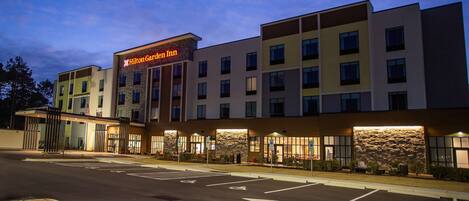 A modern hotel with a prominent sign, multiple floors, and a well-lit entrance.