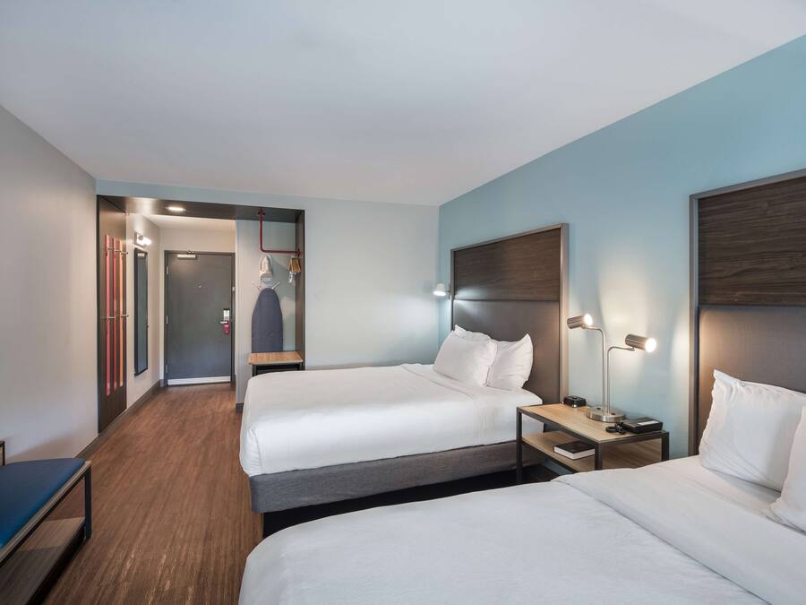 Habitación de hotel con dos camas, un escritorio, una silla y un armario.