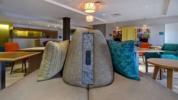 Un moderno vestíbulo de hotel con recepción, zona de estar y comedor.