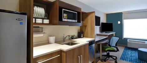 A compact kitchen with a refrigerator, microwave, sink, and a small dining area.