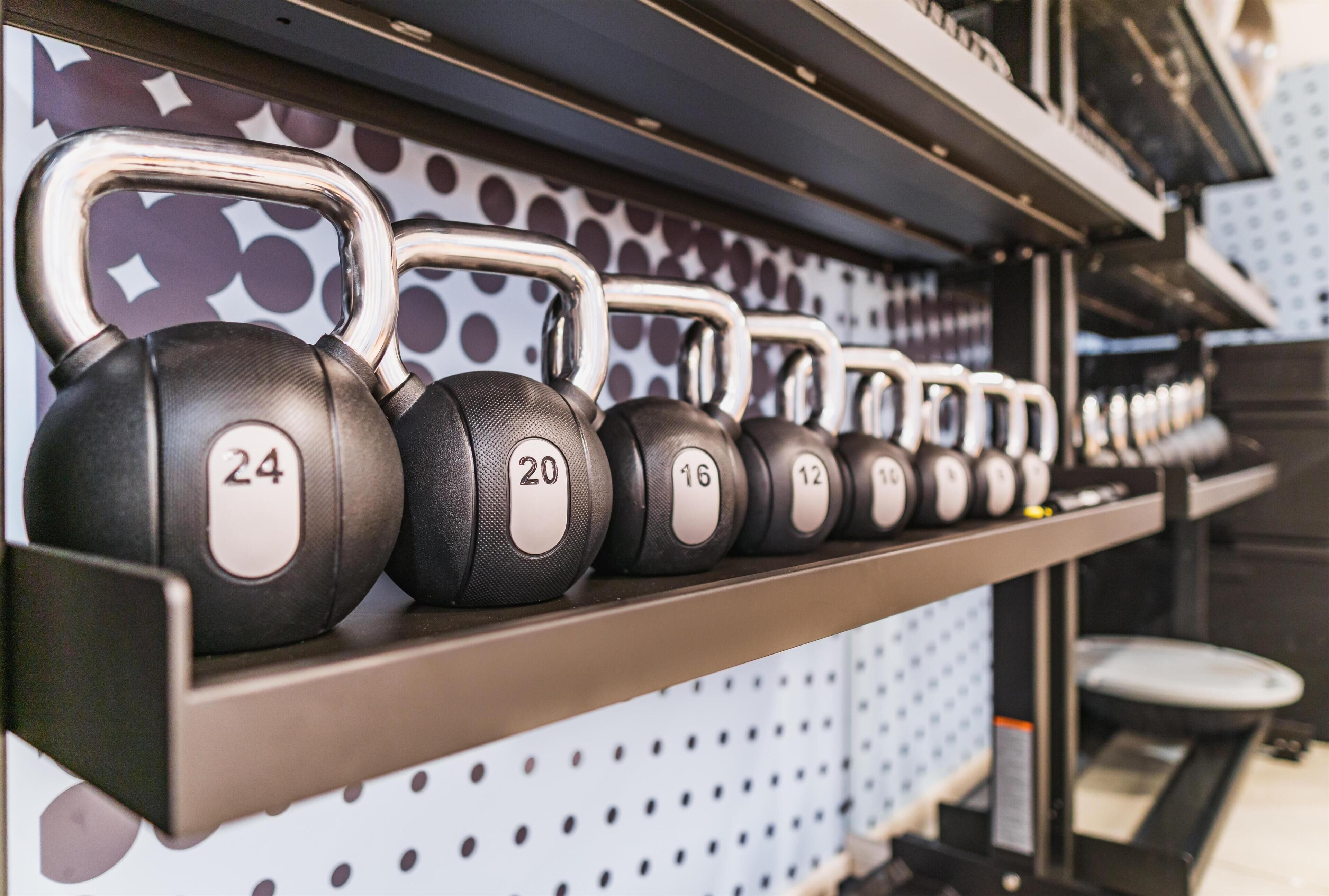 A weightlifting bench with kettlebells labeled from 12 to 24.
