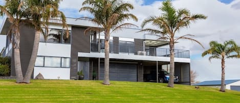 A modern two-story house with a flat roof, large windows, and a covered garage.