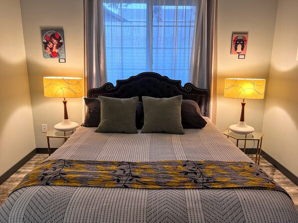 A neatly made bed with a patterned bedspread, two matching pillows, and a headboard. There are two bedside lamps on either side of the bed.