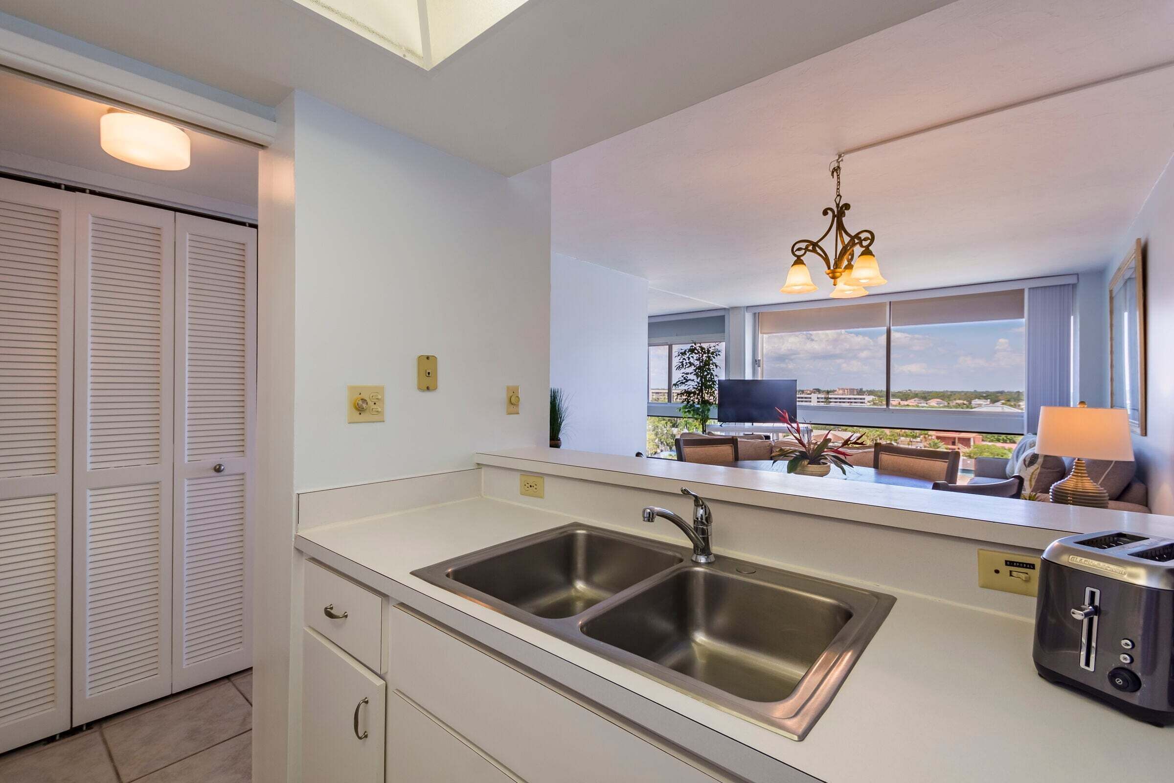A modern kitchen with a double sink, a toaster, and a view of the outdoors.