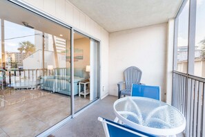 A balcony with a glass door leading to a living area, a round glass table, and a blue chair.
