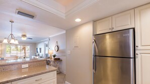 Cocina con refrigerador de acero inoxidable, encimeras de granito y muebles de cocina blancos.