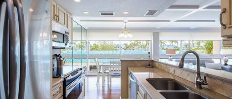 Una cocina moderna con electrodomésticos de acero inoxidable, un comedor con vistas y un amplio ventanal.