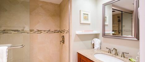 A modern bathroom with a glass-enclosed shower, a vanity with a sink, and a large mirror.