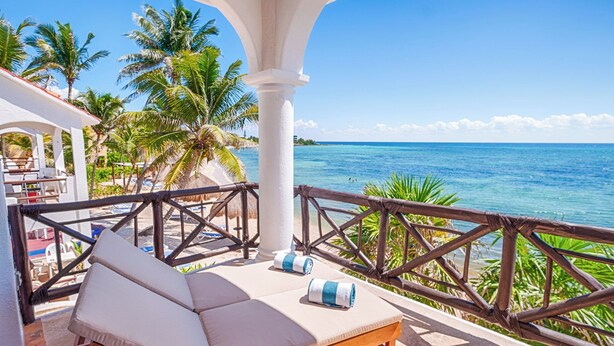 A balcony with a lounge chair and a view of the ocean. - Newly Updated Beachfront Condo with Terrace, Pool & Daily Service (Akumal)