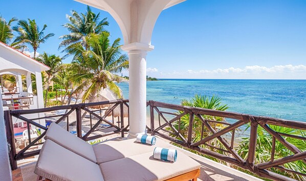 A balcony with a lounge chair and a view of the ocean. - Newly Updated Beachfront Condo with Terrace, Pool & Daily Service (Akumal)