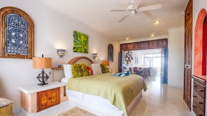A spacious bedroom with a large bed, a ceiling fan, and a view of the balcony. - Oceanview Condo with Balconies, Pool & Daily Service (Akumal)
