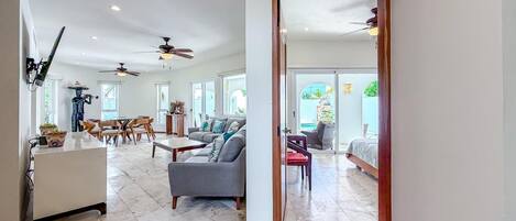 A spacious living area with a sofa, coffee table, and ceiling fans.