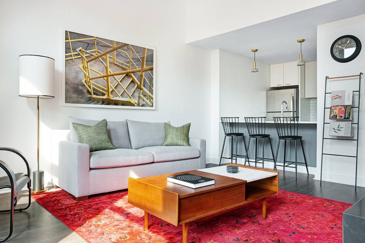 A modern living room with a sofa, coffee table, and a red patterned rug.