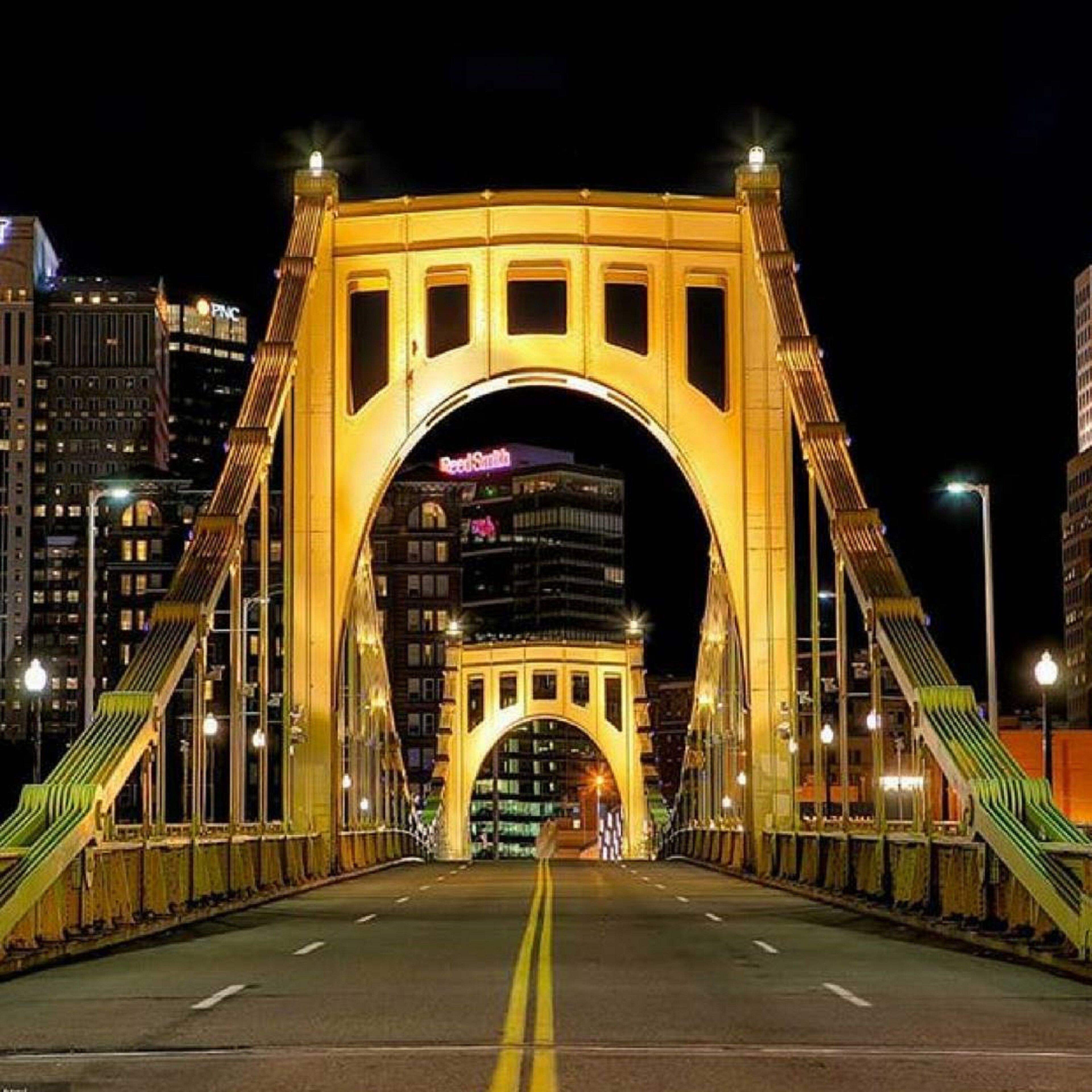 A bridge with a large arch and two symmetrical sides, featuring a road with yellow lines in the center.