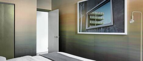 Habitación de hotel moderna con una cama, una puerta y un cuadro grande con una imagen de un edificio.