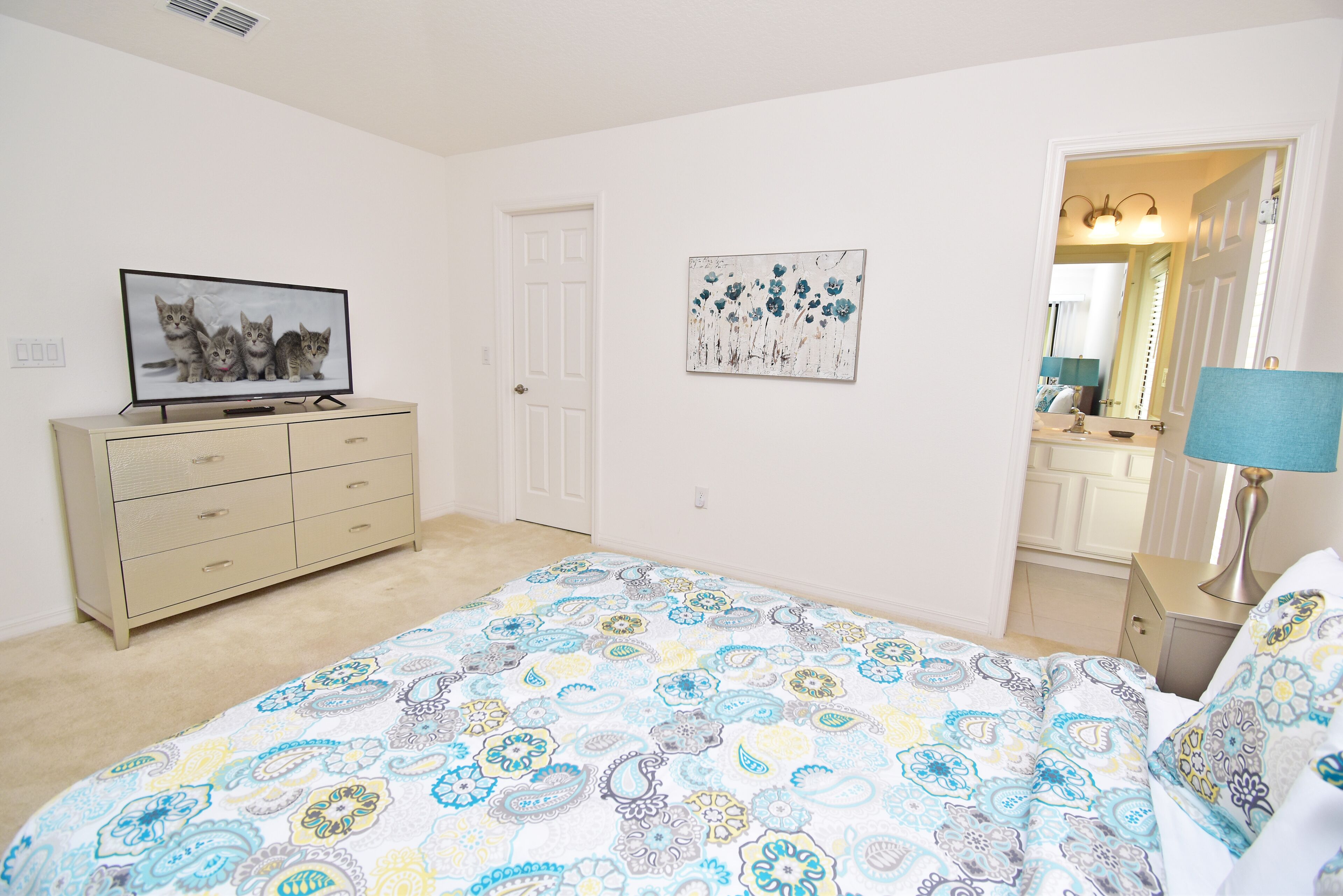 A bedroom with a bed, dresser, and a television on the dresser.