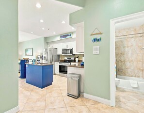 A modern kitchen with a central island, stainless steel appliances, and a hanging laundry rack.