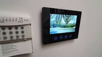 A security system with a keypad and a screen displaying a view of a street.