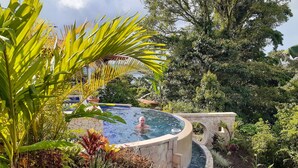 Un jacuzzi rodeado de exuberante vegetación y arquitectura de piedra.