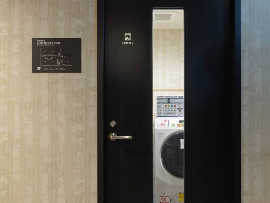A door with a laundry machine inside, a sign indicating an evacuation route map, and a wall with a patterned design.
