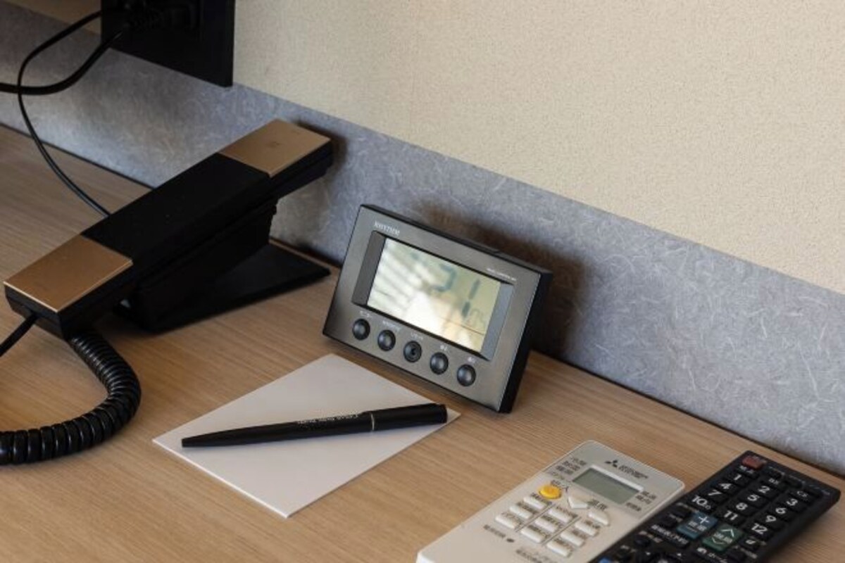 A desk with a telephone, a pen, and a calculator.