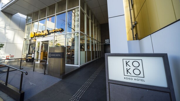 The exterior of the Koko Hotel with a clear glass facade, a visible entrance, and a signboard. - KOKO HOTEL Fukuoka Tenjin (Fukuoka)