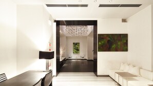 A modern hotel lobby with a long reception desk, a seating area with a sofa and chairs, and a large abstract painting on the wall. - KOKO HOTEL Fukuoka Tenjin (Fukuoka)
