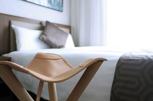 A hotel room with a bed, a headboard, and a chair.
