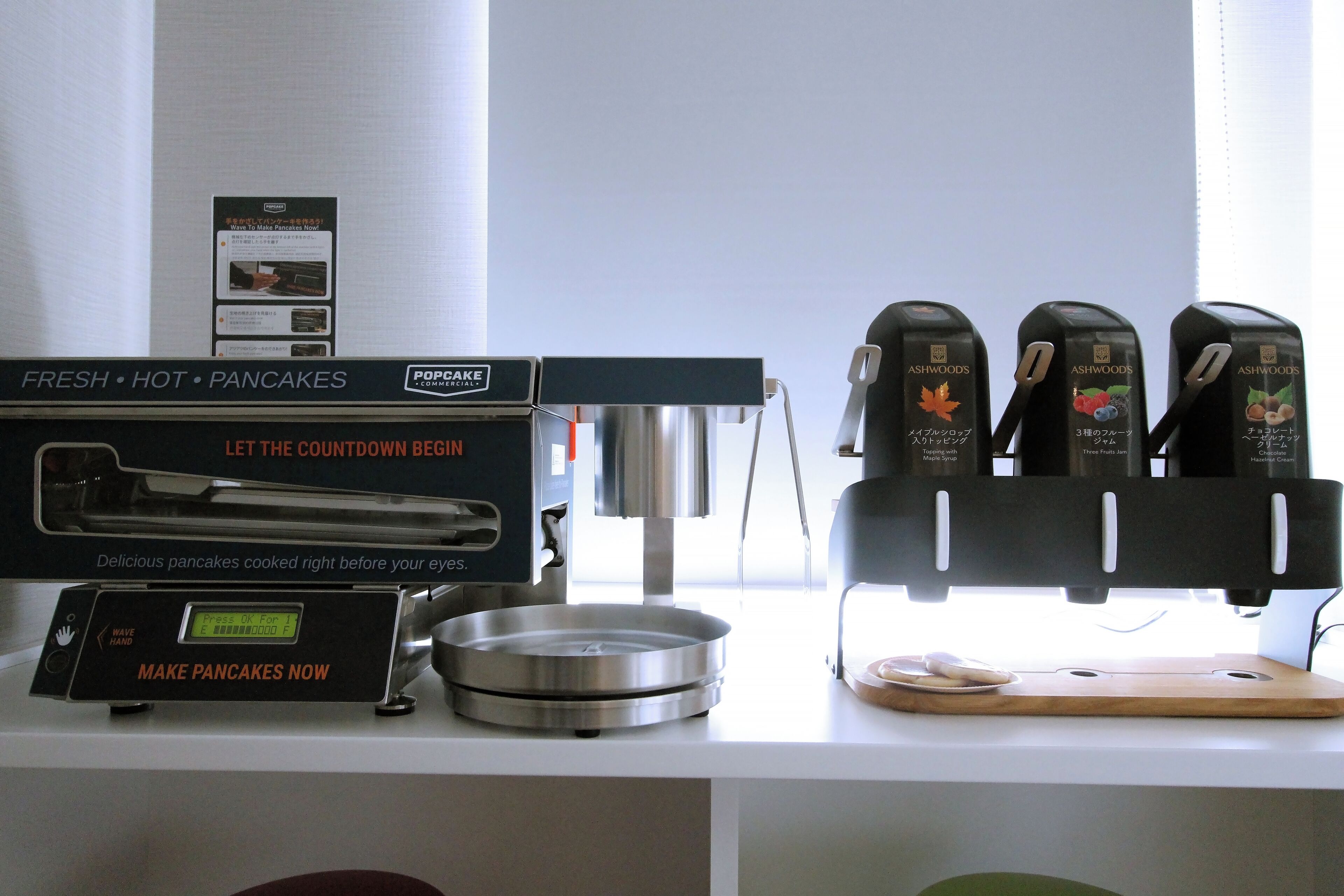 Una encimera de cocina con un preparador de Popcake, un temporizador digital y una cafetera.