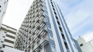 Un hôtel moderne, reconnaissable à son grand panneau « KOKO », qui se distingue par sa façade élégante et un jardin vertical sur le côté.