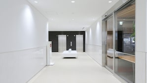 Un couloir moderne avec un comptoir d’accueil, un espace d’attente et une porte vitrée donnant sur une pièce.