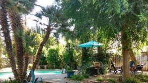 Un jardín ajardinado con piscina, palmeras y mobiliario para exteriores.
