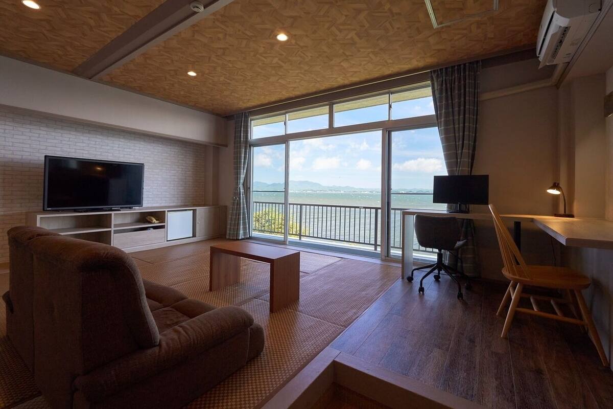 Una sala de estar moderna con sofá, televisión y un balcón con vistas.
