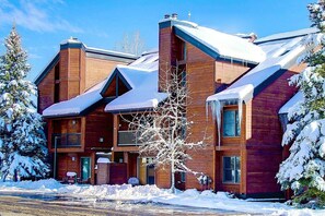 A multi-story wooden lodge with a snow-covered roof and a balcony on the second floor.
