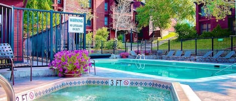 Piscina con una profundidad máxima de 3 pies, rodeada por una valla, con un letrero de advertencia y sillas de descanso.