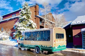 A Steamboat Resorts bus parked in a snowy area with a building in the background.