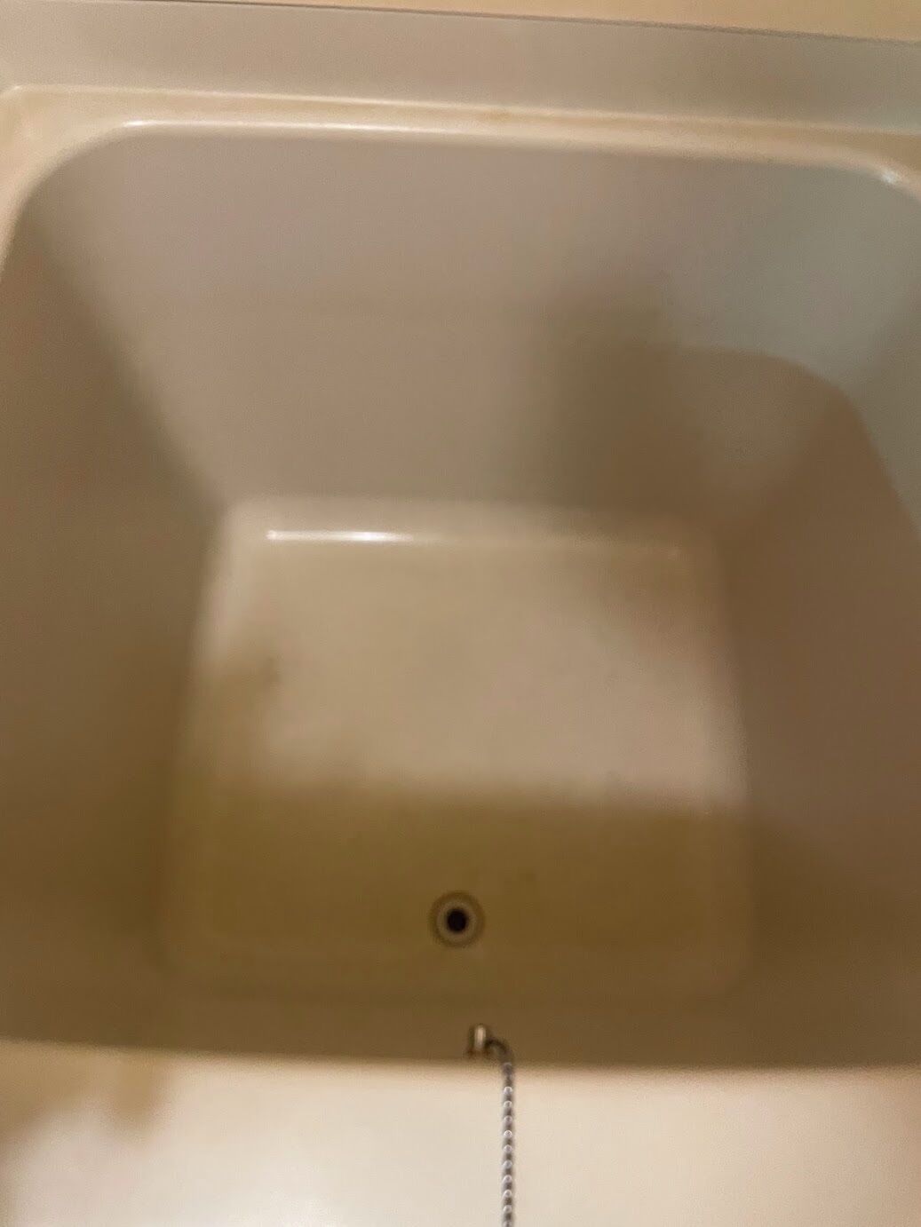 A white bathtub with a drain and a chain.