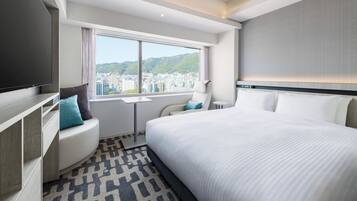 A modern hotel room with a large bed, a seating area with a view, and a flat-screen TV.