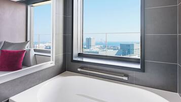 Un baño moderno con una bañera grande, una ventana con vistas a la ciudad y un perchero para toallas.