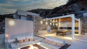 A modern outdoor living area with a fire pit, seating, and a dining setup. - Villa Hyperion - Luxury 7 bdrm Villa with infinity heated pool  (Rodia)