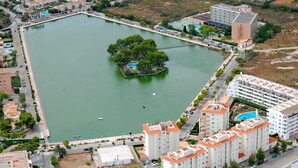 A large rectangular water body surrounded by buildings, including a hotel with multiple floors and balconies. - Family House in Port of Alcudia | Pool, Terrace & 11 min Walk to Beach (Puerto de Alcudia)