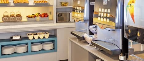 A breakfast bar with a coffee machine, fruit display, and stacked plates.