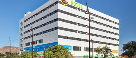 Un hotel B&B amb un disseny modern, diverses plantes i un pàrquing davant.