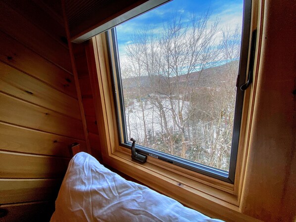 Una habitación con ventana, paredes de madera y una cama.