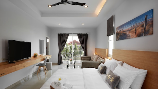 A modern hotel room with a large bed, a desk, a television, and a view of the outdoors. - Gala Express (Pattaya)