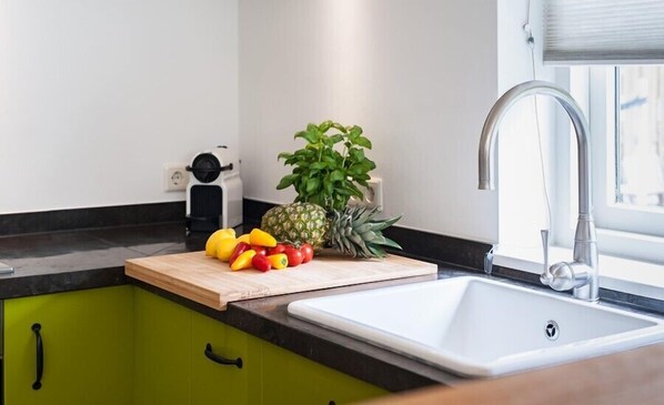 Une cuisine avec une planche à découper, des fruits et un évier.
